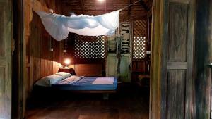 Un dormitorio pequeño con una cama con mosquitero encima. en Traditional Lanna house near hot spring, en Chiang Dao