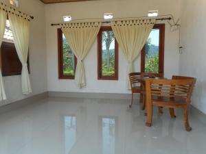 a dining room with a table and chairs and windows at Lila Stana - Sidemen Homestay in Sidemen