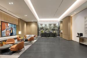 a lobby of a hotel with orange chairs and a fireplace at Citadines Hope City Boao in Qionghai