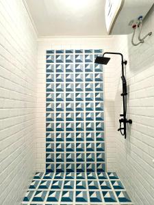 bagno con doccia e piastrelle bianche e blu di Casa Bonita: Stylish, Affordable Home & Mini Pool a Kalasan