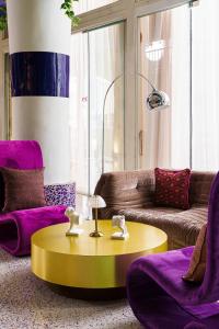 a living room with a yellow table and purple chairs at The Fig Lobby in Bangkok