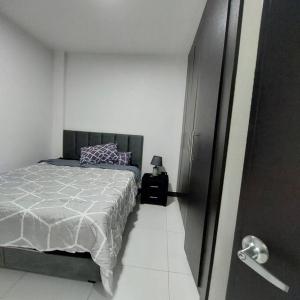 a bedroom with a bed in a white room at departamento con piscina y áreas sociales in Santo Domingo de los Colorados
