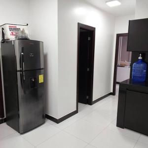 a kitchen with a black refrigerator in a room at departamento con piscina y áreas sociales in Santo Domingo de los Colorados