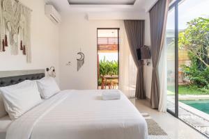 a white bedroom with a bed and a pool at Kamaratih Villas by Maheswara in Legian