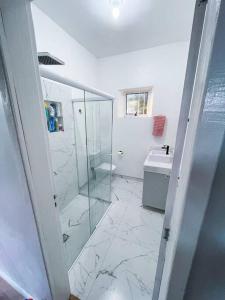 ein Bad mit einer Glasdusche und einem Waschbecken in der Unterkunft Casa aconchegante em São Gabriel in São Gabriel