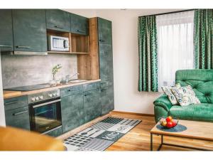 Apartment in Hohentauern with sauna في هوهنتاورن: غرفة معيشة مع أريكة خضراء ومطبخ