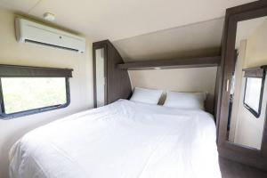 um quarto com uma cama branca num trailer em Natural farm Zanpa -SEVEN Hotels and Resorts- em Yomitan