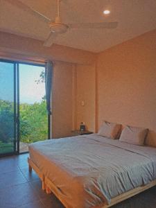 um quarto com uma cama grande e uma janela grande em CASA EBANO em Zipolite