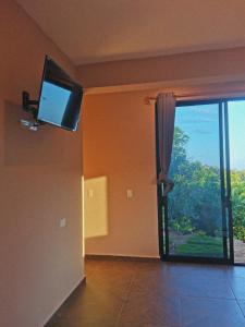 uma sala de estar com uma televisão e uma porta de vidro deslizante em CASA EBANO em Zipolite