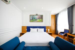 Habitación de hotel con 1 cama y 2 sillas azules en Vivian Airport Hotel Saigon, en Ho Chi Minh