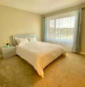 ein Schlafzimmer mit einem großen weißen Bett und einem Fenster in der Unterkunft Entire house to yourselves - NO basement sharing in Regina