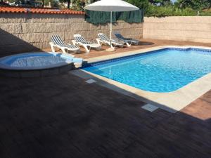 a swimming pool with two chairs and an umbrella at Pension Playa Mar Cachadiñas in Balea