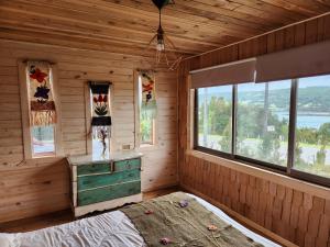 Zimmer mit einem Bett in einem Holzzimmer mit Fenstern in der Unterkunft Cabañas&tinajas en Molulco-Pureo-Natri,Compu in Compu