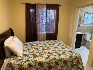 a bedroom with a bed with a floral comforter at Apartment in Montego Bay, St James - Fully Equipped For Long Term Stays in Montego Bay