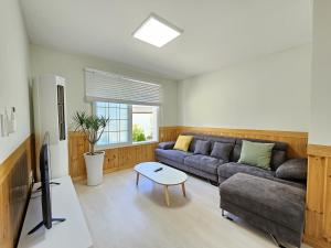 ein Wohnzimmer mit einem Sofa und einem Tisch in der Unterkunft Baerongnamu Private Stay in Seogwipo