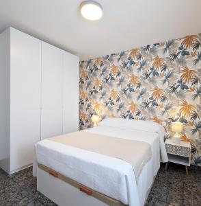 バルデペニャスにあるLa posada de Calixtoの白いベッドと花の壁紙が備わるベッドルーム1室が備わります。