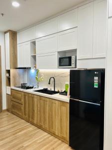 a kitchen with a black refrigerator and wooden cabinets at Thóc Ecopark blue home-1 bed room in Cong Luận