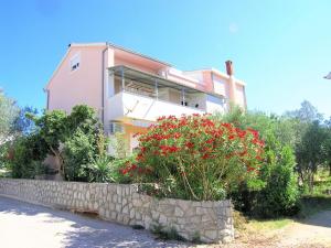 a pink house with a stone wall and red flowers at Apartment Miroslav in Krk
