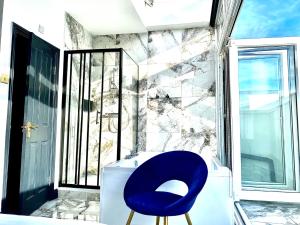 een blauwe stoel in een badkamer met een raam bij Duke and Duchess Apartments and Rooms - Private in Room Hot Tub Suites in Londen