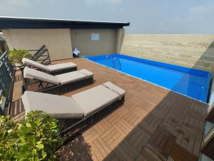 eine Terrasse mit 2 Liegestühlen und einem Pool in der Unterkunft Amika Hotel,Madurai - Near Airport in Madurai