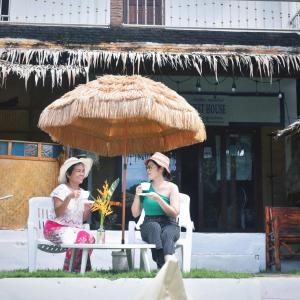 twee vrouwen zittend in stoelen onder een paraplu bij Tiki Bar-KanTiang Guesthouse in Koh Lanta