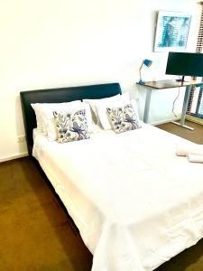 un letto con lenzuola e cuscini bianchi in una stanza di Luxurious Apartment in the heart of Docklands a Melbourne