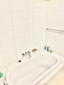 a white bath tub in a white tiled bathroom at Luxurious Apartment in the heart of Docklands in Melbourne