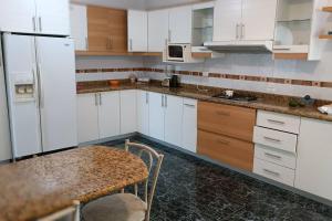 a kitchen with white cabinets and a table and a microwave at Casa de campo centro Cotacachi. in Cotacachi