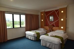 a hotel room with two beds and a window at Fair Park Premier in Ipoh