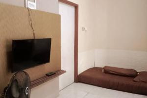 Cette chambre dispose d'une télévision murale à écran plat. dans l'établissement Florence guest house mataram lombok, à Mataram