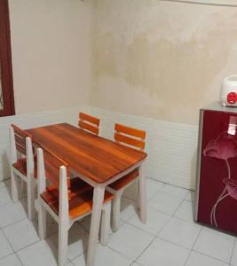 een houten tafel met 2 stoelen en een koelkast bij Florence guest house mataram lombok in Mataram