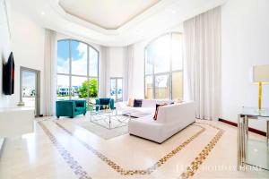a living room with white furniture and large windows at LUX - The Ocean Pearl Villa in Dubai