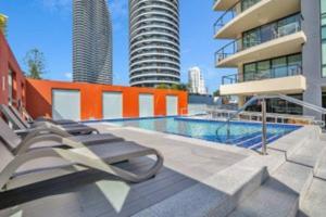 a swimming pool with two lounge chairs next to a building at Glam & Stylish Broadbeach 2BR Apartment in Gold Coast