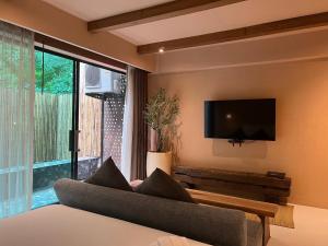 叻丕的住宿－茵拉亞拉查布里旅館，带沙发和平面电视的客厅