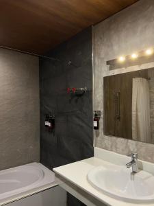 叻丕的住宿－茵拉亞拉查布里旅館，一间带水槽、浴缸和镜子的浴室