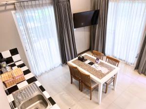 una sala da pranzo con tavolo, sedie e finestre di Bangsaen Heritage Hotel - SHA Plus Certified a Bangsaen