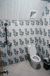 een badkamer met een toilet en een tegelwand bij Golden Orchid Villa in Diyeng