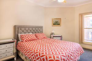 a bedroom with a bed with a red comforter and a window at Cormorant Waterfront Home in Sussex Inlet