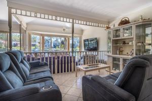 a living room with two couches and a balcony at Cormorant Waterfront Home in Sussex Inlet