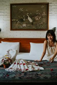 une femme assise sur un lit avec une pile de serviettes dans l'établissement Jati 3 Bungalows and Spa, à Ubud