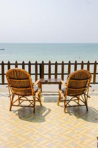 two chairs sitting next to a fence on the beach at O3 Beach Resort in Palolem