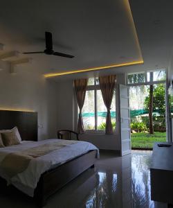 a bedroom with a bed and a large window at Mazra Retreat, Coorg Kushālnagar in Kushālnagar