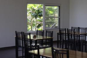 une salle à manger avec des tables et des chaises ainsi qu'une fenêtre dans l'établissement Mazra Retreat, Coorg Kushālnagar, à Kushalanagar