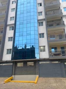 a tall building with a reflection of a building at Neema Suites, Ngong RD near Junction in Nairobi