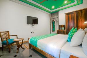 a bedroom with a bed and a chair and a tv at AAJ HAVELI - Lake Facing Boutique Hotel by Levelup Hotels in Udaipur