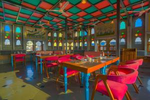 a dining room with tables and red chairs at AAJ HAVELI - Lake Facing Boutique Hotel by Levelup Hotels in Udaipur