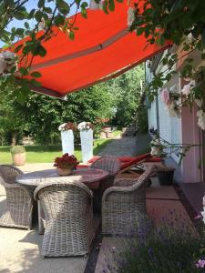 uma mesa e cadeiras sob um guarda-sol vermelho num pátio em Polderlicht em Blankenberge