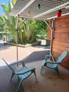 2 Stühle, ein Regenschirm, ein Tisch und ein Stuhl in der Unterkunft Les Cabanes du Voyageur in Sainte-Marie