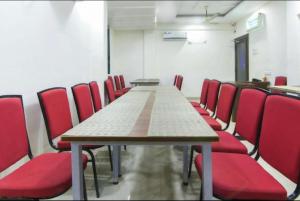 a conference room with a long table and red chairs at Hotel Ecotel in Nagaon