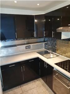 a kitchen with black cabinets and a sink at Jacuzzi Love room appartement Proche Paris in Rosny-sous-Bois